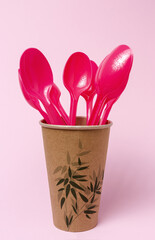 Plastic disposable tableware, forks, spoons, glasses on colored background