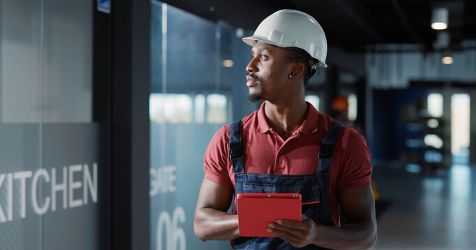 Diverse couple of adult and young electricians coworking in corporate office center repairing lighting electric system using tablet computer for management.