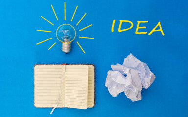 idea notebook with a light bulb on top with drawing and marking an idea together with a crumpled paper concept initiative of ideas to start a business