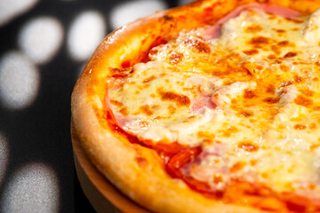 Pizza is not a wooden board. Black background. close-up.