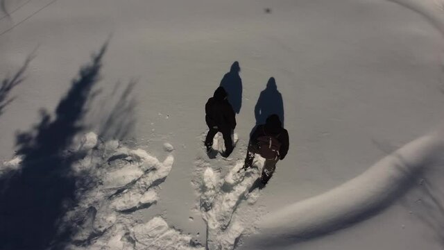 Zooming out shot by a drone, featuring two documentarians standing near a 4G and 5G communication tower, causing pollution in a snow covered area