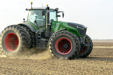 Obraz premium A large tractor with a plow is working in the field. Tillage before sowing. Loosening and plowing the soil before planting wheat and other cereals. Agricultural work.