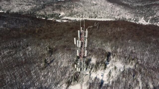 A full 360 degree drone video, featuring a marvelous 4G and 5G telecommunication tower, standing tall in a beautiful isolated snow covered area.