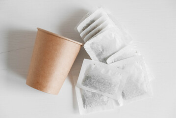 Paper cup and bags with tea on a white background. Top view. Copy, empty space for text