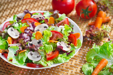 Dish of Lettuce salad mixed with sliced common mushroom (Agaricus bisporus), tomatoes and carrots