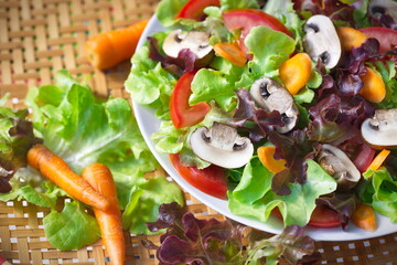 Dish of Lettuce salad mixed with sliced common mushroom (Agaricus bisporus), tomatoes and carrots