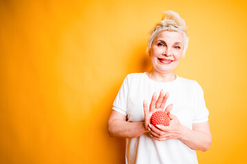 Happy elderly woman holding a small rubber ball for muscle relaxation and running it in the palm of her hand