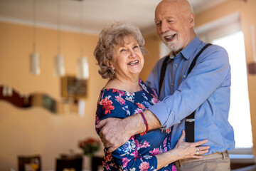 Happy senior couple dancing together at home
