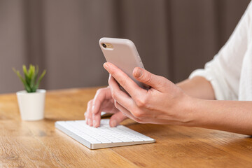 woman hands close up working on white computer keyboard and smartphone, work from home concept. work online, shopping