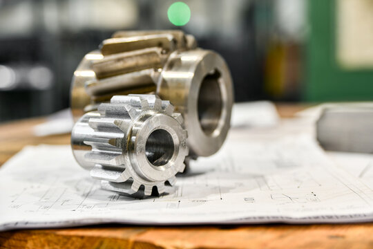A cogwheel made on a gear cutting machine lies on the technical drawings.