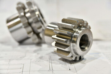 A cogwheel made on a gear cutting machine lies on the technical drawings.