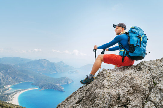 Young backpacker man sitting on cliff and enjoying the Mediterranean Sea bay at during Lycian Way trekking walk. Famous Likya Yolu Turkish route. Active sporty people vacations concept image