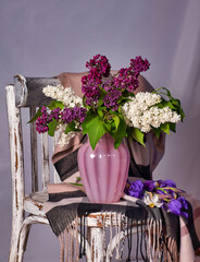 Lillac bouquet in vase on Vintage wooden chair