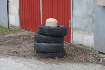 one brown iron restraining post with black old car tires on the street against the wall