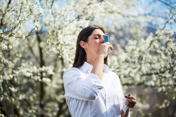 Young woman uses an inhaler outdoor