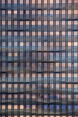 Skyscrapers building detail reflections on windows. The blue sky with clouds reflected on the facade of a businness building