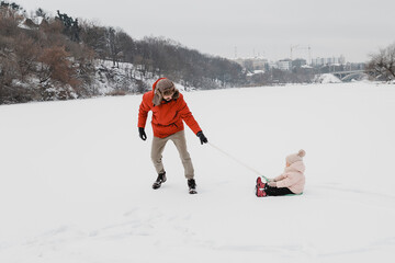Young stylish bearded Father and baby Daughter On Winter Vacation. Father giving son ride on back in park. Happy, joyful family. Happy, joyful family.