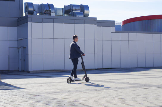 Young Business Man In A Suit Riding An Electric Scooter On A Business Meeting