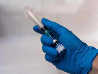 A doctor holds a syringe aspirating a dosis of a recently developed COVID-19 vaccine ready to inject in a patient's arm in order to provide immunity against this condition trying to collaborate to sto