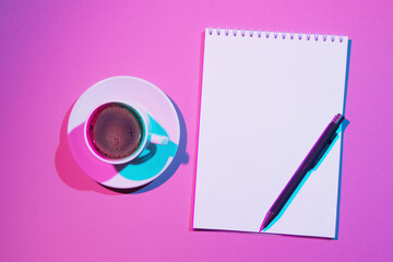Blank note book and cup of coffee on pink background. Double colorful shadows