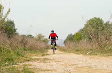 Obraz premium Male cyclist pedaling down a dirt road with a mountain bike. Effort, competition