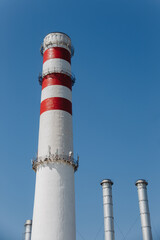 Factory chimney on blue sky. Concept of steam plant, air pollution, heating season