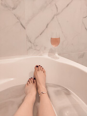  Woman with glass of wine in bath. Sunday relax concept