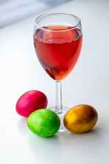 The glass of red wine or Cahors and Easter eggs on the table.