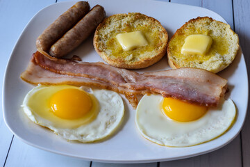 breakfast plate of eggs bacon sausage with  english muffin