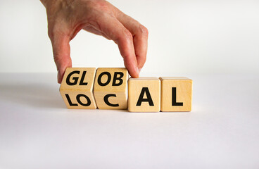 Local or global symbol. Businessman turns wooden cubes and changes the word 'local' to 'global'. Beautiful white table, white background. Business and local or global concept. Copy space.