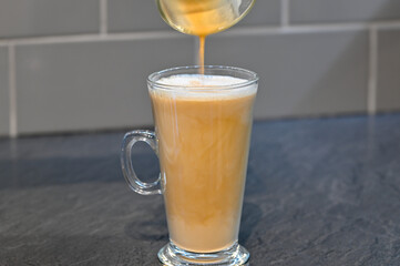 Pouring an espresso into hot milk to make a home made latte