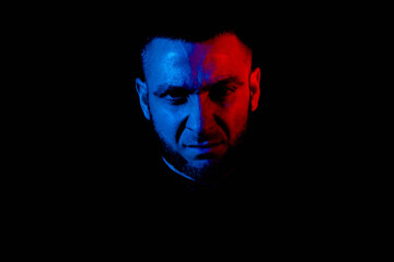 Portrait of a serious Caucasian guy illuminated by red and blue light. Cyberpunk.