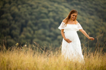 Fototapeta na wymiar Young pregnant woman at the field