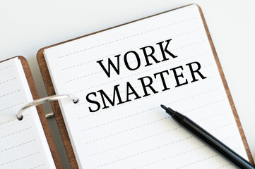 Work Smarter text written on notebook page next to black marker. Concept image