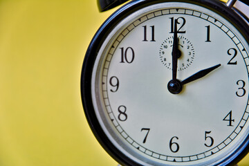 Shot of vintage retro analog clock on yellow background showing 2 o clock
