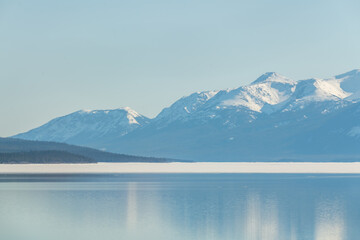 Spring time views in northern Canada with pristine, blue sky day, perfect glassy, calm water below and partially frozen lake below. Perfect for desktop, wallpaper, tourism shot, scenic view. 