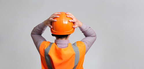 back of contruction worker clutching his head in helmet on grey studio background looking, foreman...