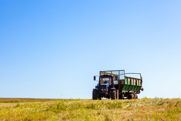 Tractor with a trailer in the field for agricultural work. 