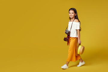 cute little girl with retro camera on yellow background.