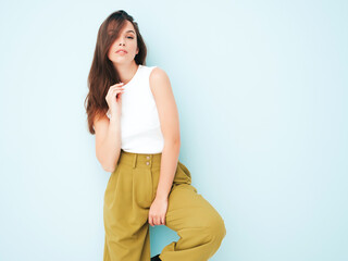 Young beautiful smiling female in trendy summer suit clothes. Sexy carefree woman posing near light blue wall in studio. Positive model having fun indoors. Cheerful and happy