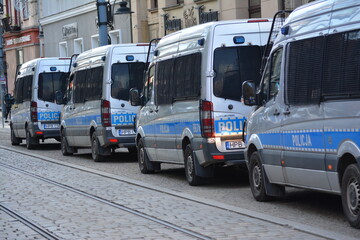 Srebrno szare samochody policyjne z niebieskim napisem policja. 