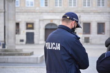 Polski policjant w niebieskim mundurze z napisem policja.  © FotoDax