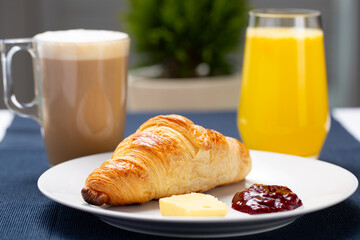 Croissant served on a table with cappuccino and orange juice for breakfast 