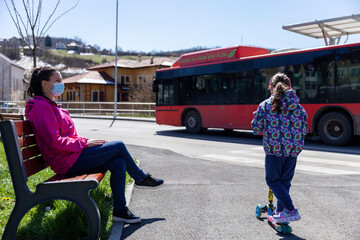 A young mother with a female child at a bus stop