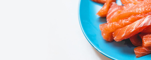 Delicious cut raw salmon fillets served on a blue plate and ready for prepare sushi in the kitchen of a restaurant 