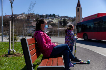 A young mother with a female child at a bus stop