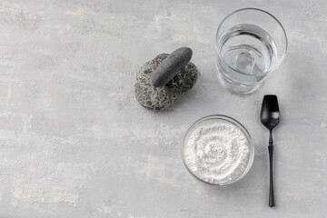 A glass of water, collagen powder on a light background. Healthy lifestyle concept. Hydrolyzed collagen in a glass cup and black spoon. Natural supplement. Copy space.