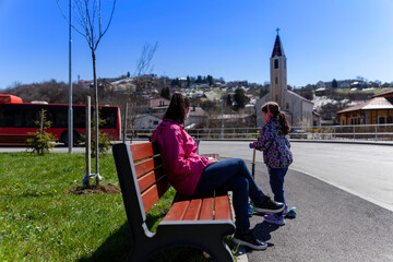 A young mother with a female child at a bus stop