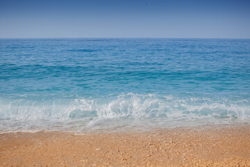 Closeup shoot of calm sea waves and foam on the sand beach.