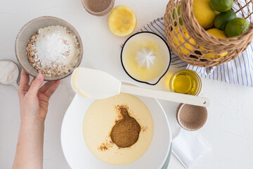 Bowl full of flour and cereal about to be poured by a woman hand into a muffin batter.